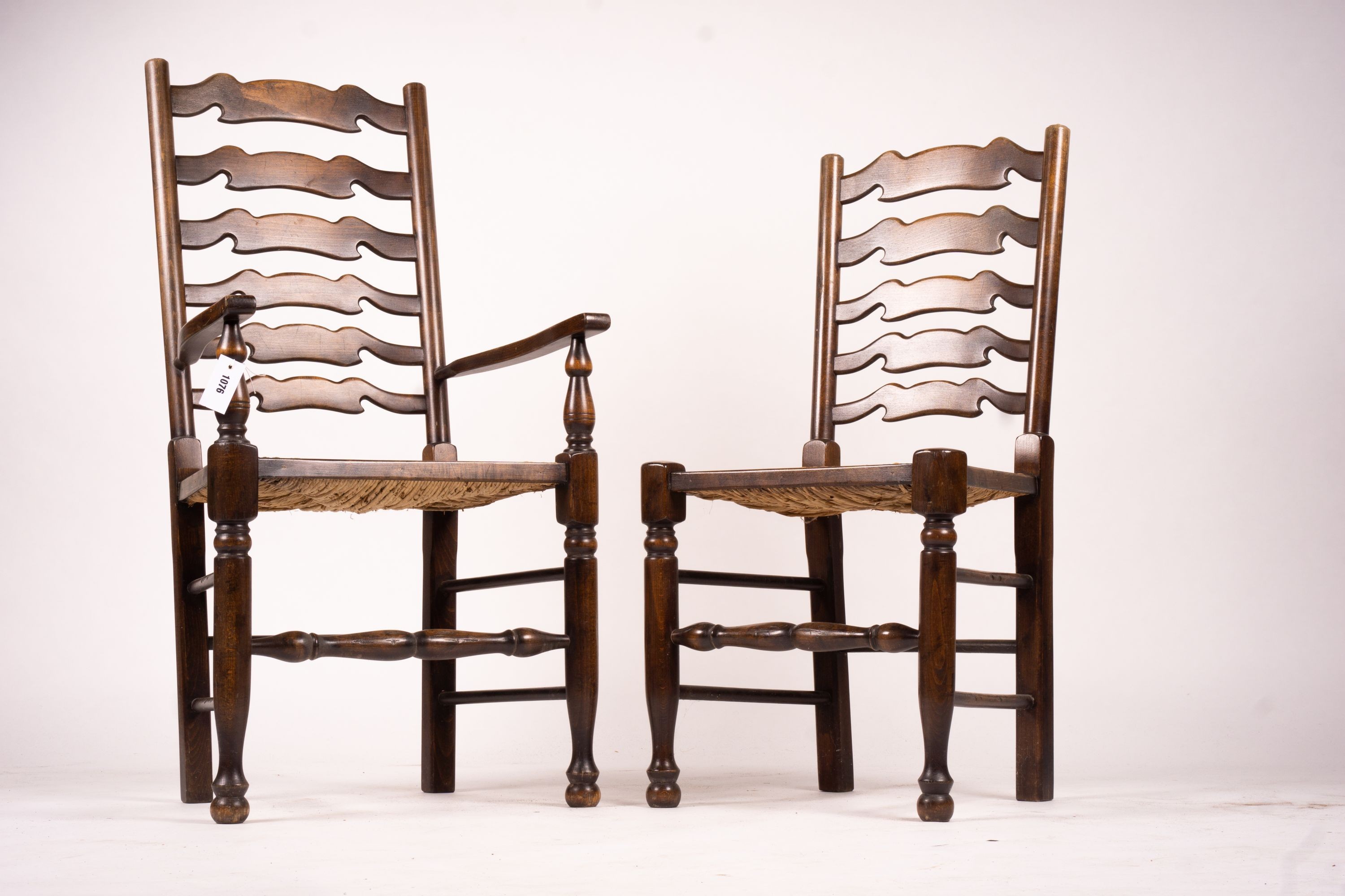 A set of ten 18th century style beech ladderback rush seat dining chairs, two with arms